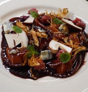 RAVIOLI RIPIENI AL GORGONZOLA DOLCE IGOR CON FUNGHI PORCINI, SALSICCIA DI BRA E PORRI FRITTI